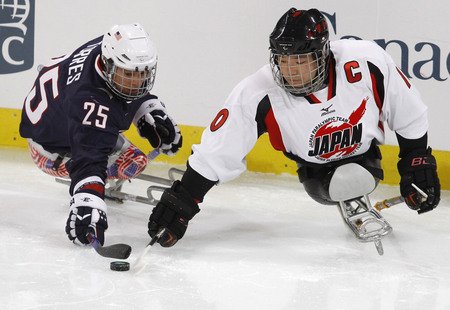 Ilya Pitalev. Bubba Torres,  USA Ice Sledge Hockey player, goes for the puck against the Japanese team. Vancouver, Canada