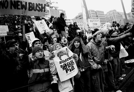 Anthony Suau.
Washington DC, USA. 
January 20, 2001. 
Protesters demonstrate against the inauguration of US President George W. Bush at Freedom Square as the Bush's motor car passes down Pennsylvania Avenue. 
Anthony Suau © 2001