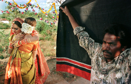 Jonathan Torgovnik.
Actresses Madooh and Urmila embrace, and a film crew man blocking the light from the camera by hand holding a black cloth. As labor is very cheap in India, this film crew worker is acting as a human “flag” for blocking the light.
1997.
Presented by Admira, Milan