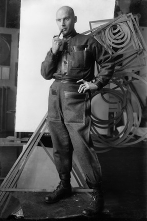 Mikhail Kaufman.
Alexander Rodchenko in the studio dressed in the industrial costume against a background of the spatial constructions. 
1924. 
The collection of the Moscow House of Photography